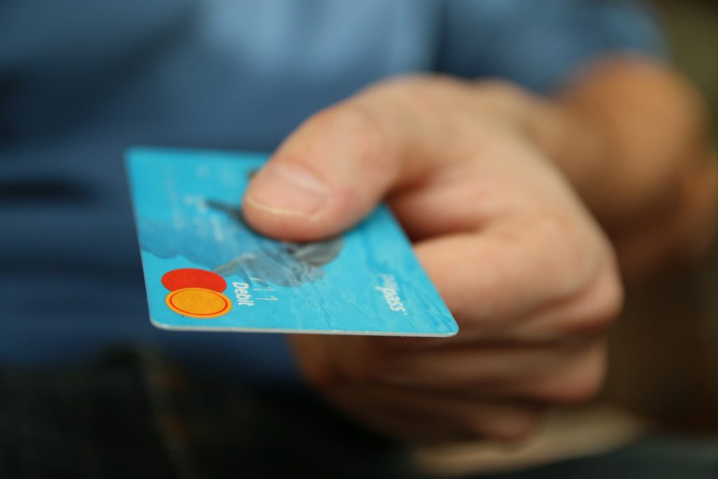 Man holding out a blue debit card
