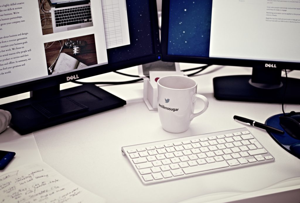 blogger desk featuring computer, keyboard, coffee mug and pen