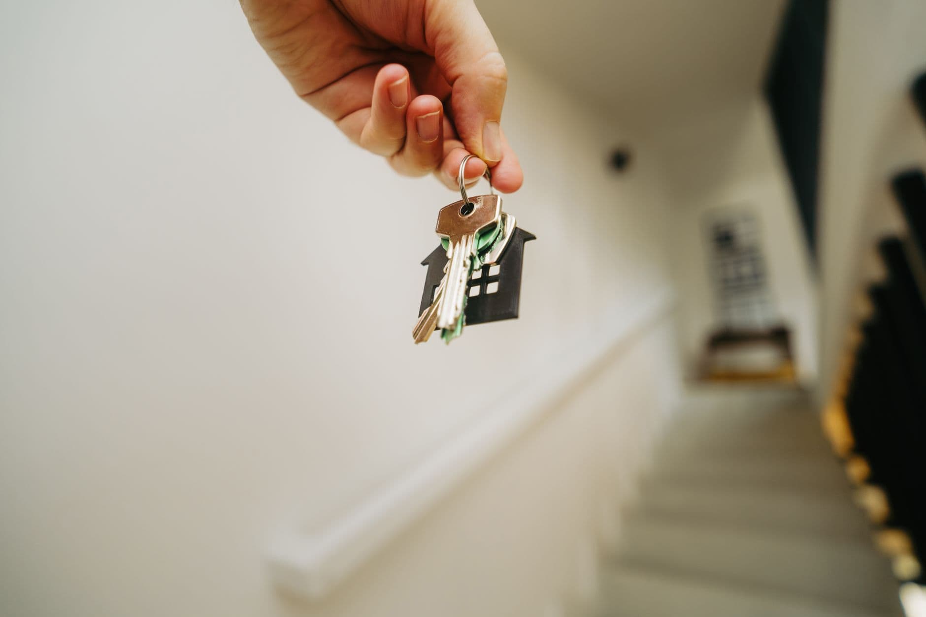 hand holding house keychain symbolizing real estate